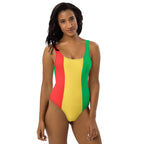 A confident Black woman models the swimsuit in a bold stance with natural curls and hoop earrings, shot against a vibrant blue background that complements the colors of the suit.